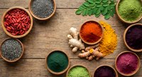 Colorful superfood powders and seeds in wooden bowls on rustic table. Healthy nutrition ingredients including turmeric, spirulina, goji berries for cooking.