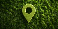 Green location pin marker on natural grass moss background, representing eco-friendly navigation and sustainable business concepts.