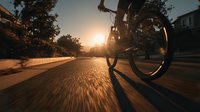Silhouette of cyclist riding bike on suburban street at sunset with motion blur effect creating dynamic perspective.