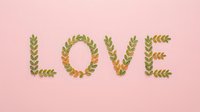 Romantic LOVE word spelled with green leaves and branches on soft pink background for wedding invitations and Valentine's Day cards.