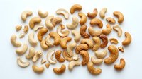Raw cashew nuts scattered on white background, healthy snacking and cooking ingredient for recipes and meal preparation.