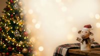 Decorated evergreen tree with golden lights and ornaments beside wooden trunk holding snowman figurine wearing red hat against warm bokeh background.