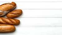 Fresh crusty French baguettes arranged on white wooden background with copy space. Traditional artisanal bread composition for bakery or food design.