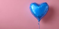 Blue heart-shaped foil balloon against pink background, perfect for celebration, romance, or party decoration concepts.