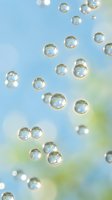 Floating soap bubbles against soft blue and green blurred background creating dreamy atmosphere for relaxation and wellness concepts.