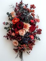 Moody floral arrangement with burgundy and peach roses, dahlias, and dark eucalyptus leaves on white background, creating dramatic contrast for wedding decor.