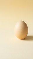 Single brown chicken egg standing upright on neutral beige background with soft lighting and minimal shadow for cooking and food photography concepts.