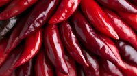 Fresh red hot chili peppers in macro view showing glossy texture and vibrant color, arranged in rows for food photography and culinary design use.