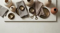 Handmade ceramic pottery collection with earthy tones and linen napkins arranged on neutral background for modern kitchen and dining decor.