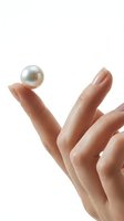 Hand holding lustrous pearl on white background, isolated for luxury jewelry, skincare, and cosmetics design applications.