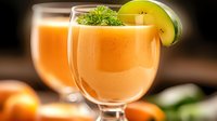Fresh orange smoothie garnished with lime slice and herbs in glass on dark background. Refreshing summer drink with citrus fruits.