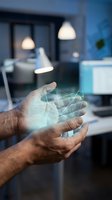 Male hands holding glowing digital network hologram in modern office workspace with pendant lights and blue interior design, representing technology innovation and data connectivity.