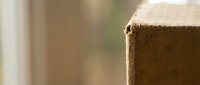 Close-up of brown cardboard box corner with soft bokeh background for shipping and packaging concepts in warm natural lighting.