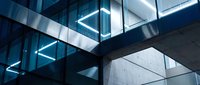 Modern architectural structure with geometric glass and concrete elements, featuring bright neon blue lighting creating contemporary aesthetic for design, tech, and corporate projects.