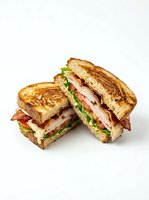 Toasted sandwich halves filled with crispy bacon, fresh lettuce, ripe tomato slices, and melted cheese between golden-brown bread. Perfect for food photography, restaurant menus, and culinary content.