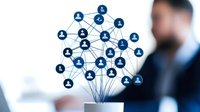 Network of connected user icons growing from laptop with businessman in background, representing social media growth and digital networking technology.
