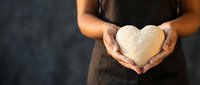 Woman hands gently holding white heart shape against dark background symbolizing love care compassion and kindness for charity wellness concepts.