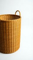Natural wicker laundry basket with handles isolated on white background for home organization and storage solutions in modern interior design.