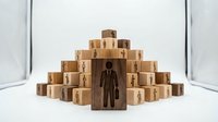 Wooden blocks arranged in pyramid formation with human figure icon on front block representing organizational hierarchy and team structure concepts.