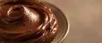 Rich chocolate frosting swirl with glossy texture perfect for baking desserts cakes cupcakes sweet treats confectionery culinary food photography bakery applications.