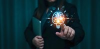 Businessman touching glowing brain lightbulb with innovation icons in dark corporate environment for creative thinking and artificial intelligence concepts.