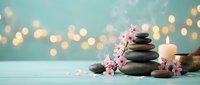 Zen spa stones with cherry blossoms and candles creating peaceful meditation atmosphere with warm bokeh lights for wellness and relaxation concepts.