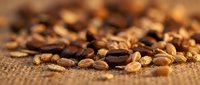 Roasted coffee beans scattered on burlap fabric surface, showcasing rich brown tones and texture for beverage, food, and café design projects.
