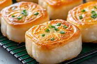 Pan-seared scallops with caramelized golden-brown crust and fresh herbs garnish on cooling rack, close up view showing delicate sear pattern and juicy texture.