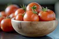 Fresh ripe red tomatoes with green stems in wooden bamboo bowl on dark background, close up view with selective focus for food photography.