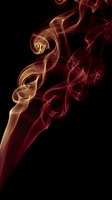 Abstract smoke swirls in golden red hues against black background creating elegant flowing patterns for luxury design projects and artistic compositions.