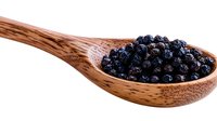 Fresh dried juniper berries in wooden spoon on white background, macro food photography for culinary and cooking projects, isolated with copy space.