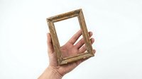 Hand holding empty wooden picture frame against white background for mockup and design projects.