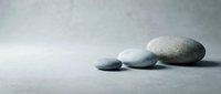 Smooth gray zen stones arranged on textured surface creating peaceful minimalist composition for meditation wellness spa and relaxation concepts.