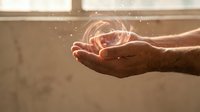 Adult male hand holding glowing orb of light with sparkling particles, representing energy, innovation, and future technology concepts for business and creative projects.