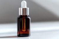 Amber glass dropper bottle with silver cap on white surface in soft natural lighting, casting gentle shadows. Essential oil or serum container for cosmetic products.