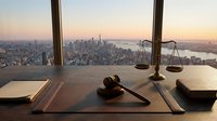 Legal office desk with gavel and scales overlooking city skyline at sunset. Professional law firm workspace for justice and legal consultation services.