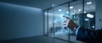 Businessman in dark suit interacting with holographic data visualization displaying financial charts and analytics on transparent digital interface in modern office environment.