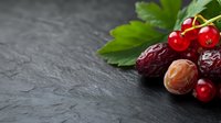 Fresh cranberries, dates and mint leaves arranged on dark slate surface for healthy eating and natural nutrition concepts.