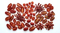 Assorted dried red spices and seasonings arranged on white background including chili peppers, beans, and aromatic ingredients for cooking.
