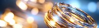 Golden wedding rings with soft bokeh lights in background, macro photography capturing romantic sparkle and metallic shine on jewelry against blurred warm glow.