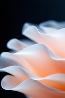 Soft waves of white paper create abstract curves against orange glow background, showcasing gentle folds and shadows in minimalist macro photography.