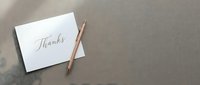 Elegant thank you card with gold pen on neutral background for gratitude messages and correspondence.