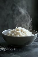 Steaming bowl of freshly cooked white rice in ceramic dish against dark background, with rising vapor capturing light for food photography.
