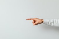 Caucasian person wearing light gray sweater pointing finger to side against white background, minimal composition for business and direction concept.