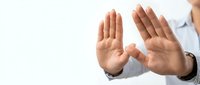 Professional businessman making stop gesture with both hands raised showing palms in defensive position against white background for business communication.