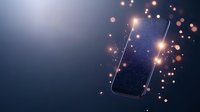 Floating smartphone with glowing screen surrounded by magical sparkles and bokeh lights against dark blue background, modern technology concept.