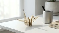 Elegant origami paper crane on clean white desk with modern office supplies and natural window light creating minimalist workspace atmosphere.