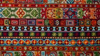 Traditional ethnic carpet with colorful geometric patterns and ornamental borders. Handwoven textile featuring vibrant folk motifs for interior design projects.