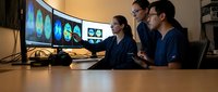 Three diverse professionals analyzing data on multiple curved monitors in modern office workspace for business intelligence and teamwork collaboration.