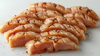 Raw salmon sashimi slices garnished with black sesame seeds and spices on light background, fresh fish fillet cut in traditional Japanese style.